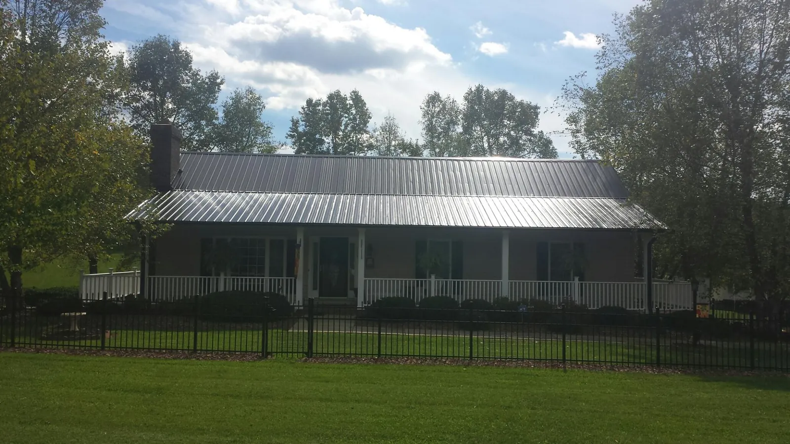 Gray metal roof on a brick ranch with a full width front porch — Gutter Guard Installation work by our crew in Mystic